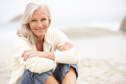 Happy senior woman sitting on the beach Happy senior woman sitting on the beach